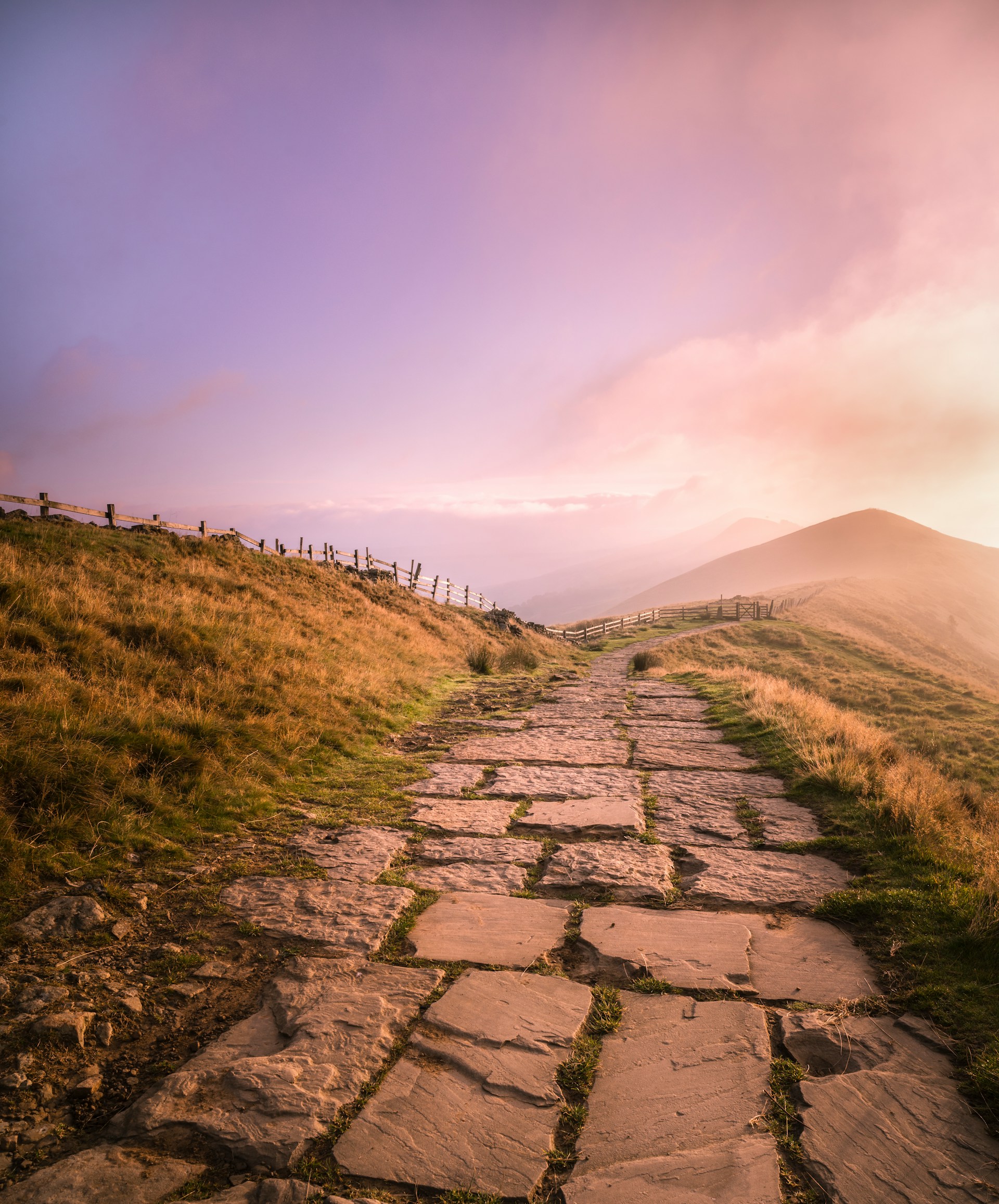 Open hills and a winding path beneath a wide sky